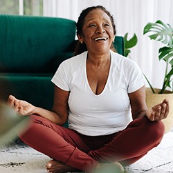 Senior woman smiling while meditating at home