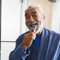 Couple smiling while brushing teeth in bathroom