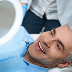 A man smiling in the mirror at his dental implants