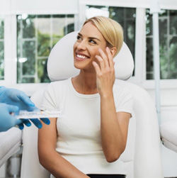 Patient smiling in treatment chair as dentist brings out BOTOX