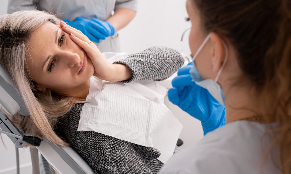 Woman in dental chair holding jaw