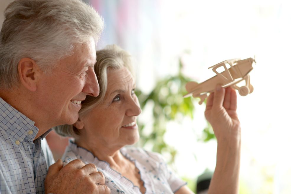 A man and a woman playing with a wooden airplane.